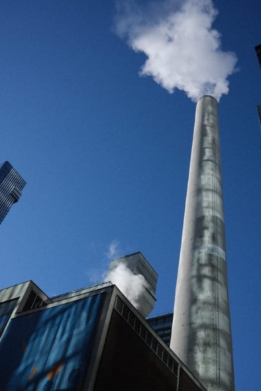 Random factory stack in downtown Toronto; blue sky in the background with steam coming out of the pipes.