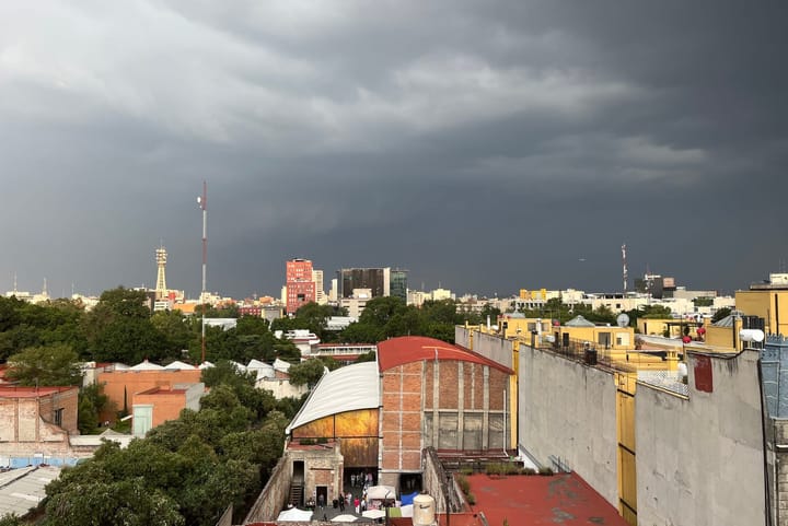 Panoramic photo of red-colored rooftops in Mexico City with a storm brewing in the background.